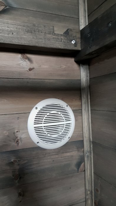 Ventilationsgaller på en mörkgrå lasyrbehandlad bastupanel.