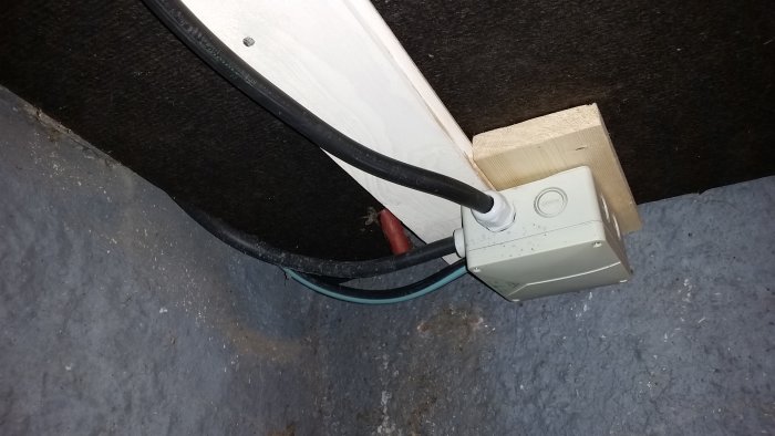 Elektrisk dosa med klamrade kablar och synlig isolering, inklusive en oskyddad skena och ändskydd.