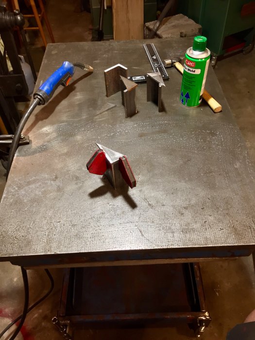 Verkstadsbord med svetstänger, gasbrännare och svetsspray redo för metalarbete.