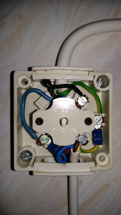 Öppen kopplingsdosa med synliga anslutna sladdar och skruvanslutningar i en vägginstallation.