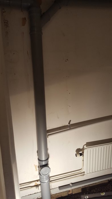 Nybinstallerade gråa avloppsstammar i ett hus, med synlig koppling och böj.