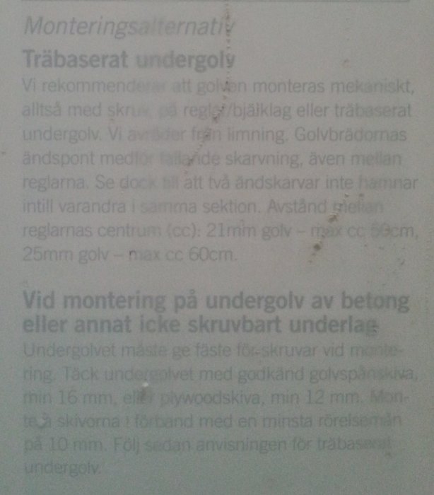Suddig bild av en instruktion för montering av träbaserat undergolv med text om avstånd för skruvning.