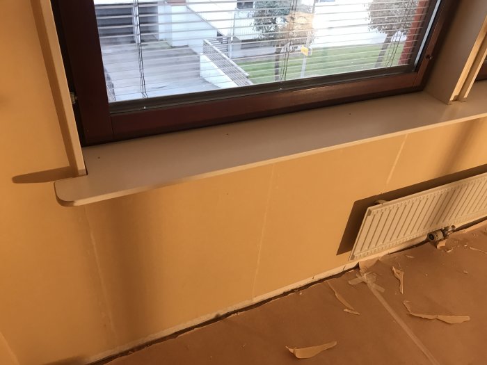 Nyinstallerad infälld fönsterbräda i ett rum under renovering, med spackling och slipningsarbete på väggarna.