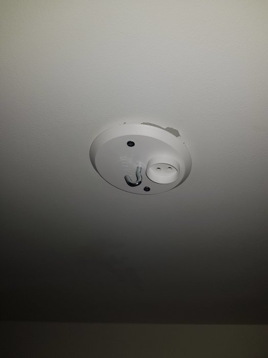 En ny vit lamphållare monterad på ett tak, med synliga skruvhål och elanslutningar.