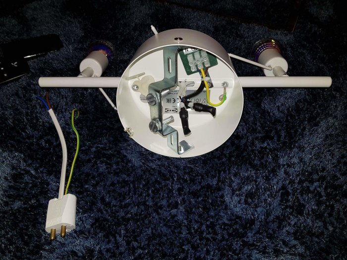 Nyinstallerad lampsockel med ledningar och kontakt mot en blå matta.