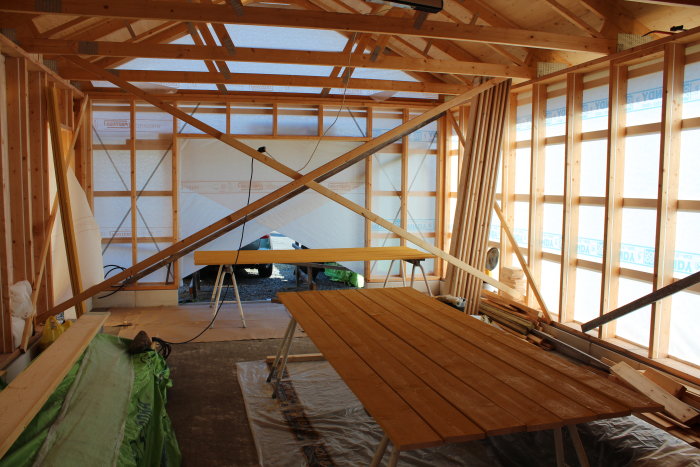 Inre hörn av en trähall under konstruktion med reglar och förstärkt dörrparti.