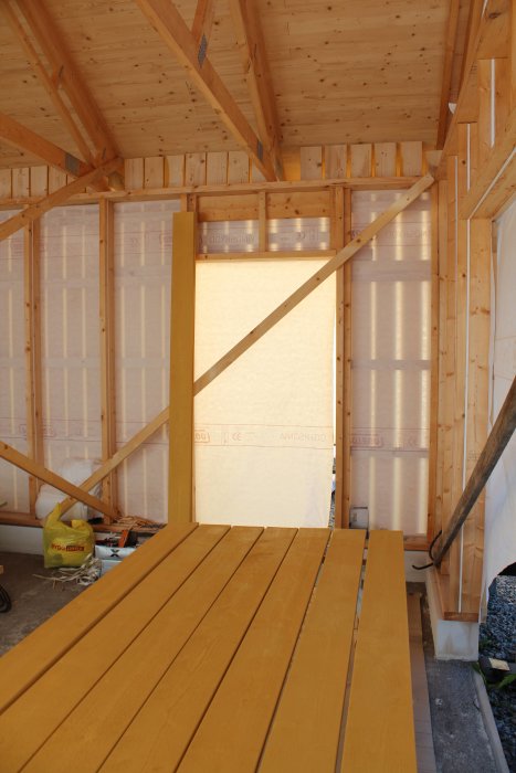 Nybyggd träkonstruktion med förstärkning vid dörren och reglar i innerhörn.