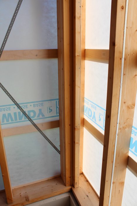 Träreglar förstärker en dörröppning i en målarverkstad med synliga isoleringsskikt.