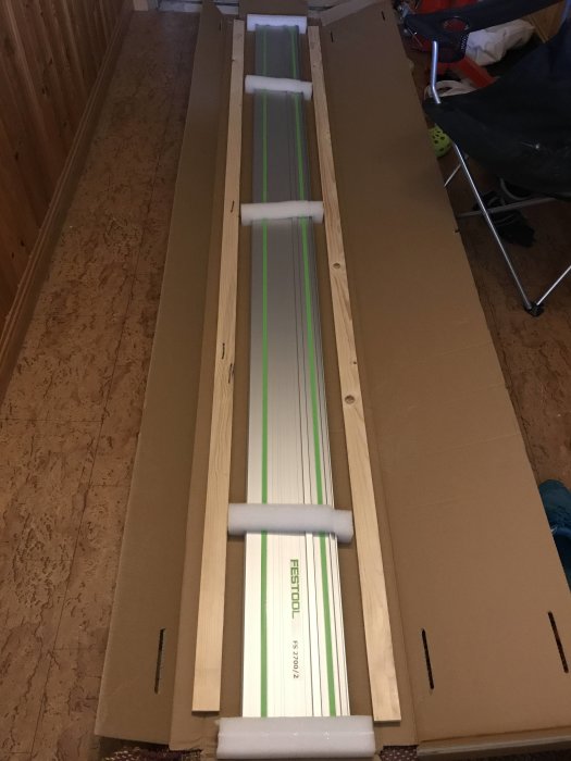 En lång sänksågskena från Festool i förpackningen stödd mot väggen.