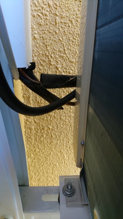 Isoleringsmaterial lossnat på rör nära utedel av luftvärmepump mot husvägg.