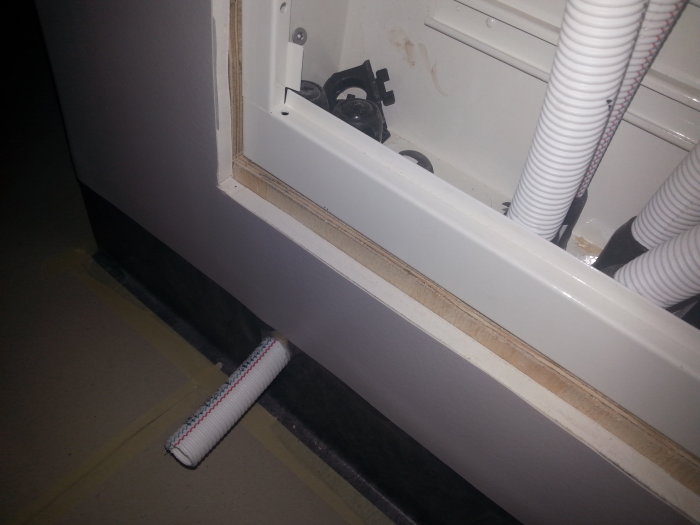 Våtrumsmatta skuren kant i kant med fördelarskåp intill vägg under renovering.
