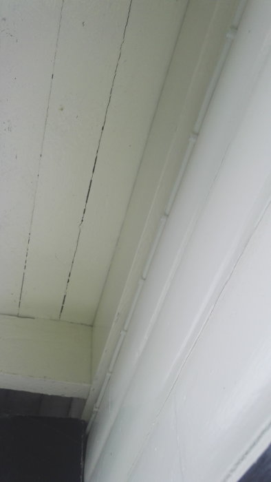 Vitmålad takregel placerad centralt mellan två takstolar, synliga i ett inomhusbyggprojekt.