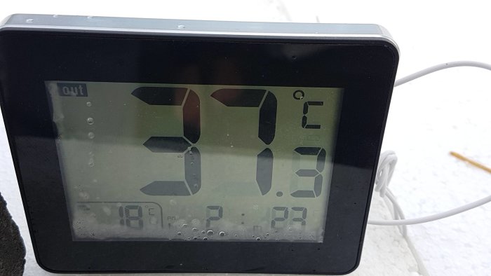 Digital termometer som visar utomhustemperatur -7.9 grader Celsius i snöväder.