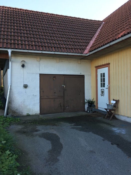 Utgångspunkt för tillbyggnad: garage och entrédörr i gult hus med rödakorrtak.