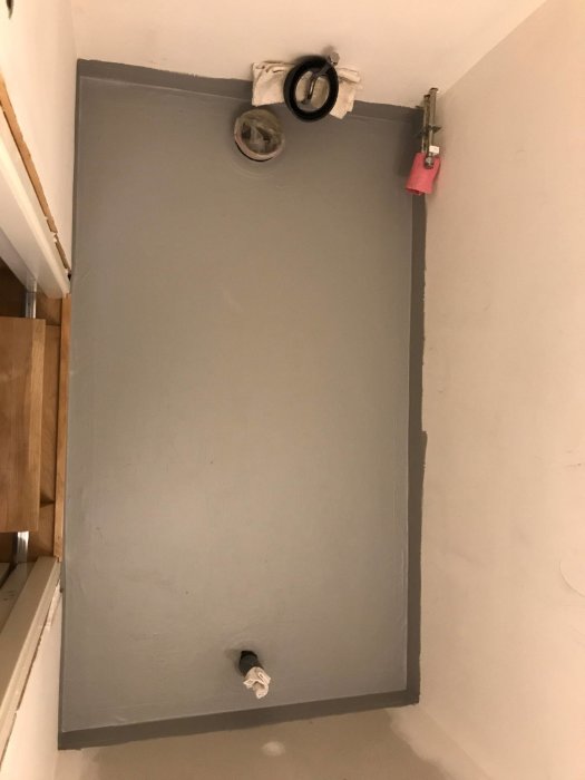 Förberedd yta för plattsättning, 90x160 cm, med synliga rör och uppstaplad handduk.