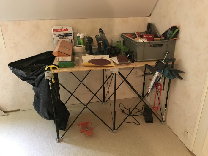Montagebord med diverse verktyg och byggmaterial i ett rum under renovering.