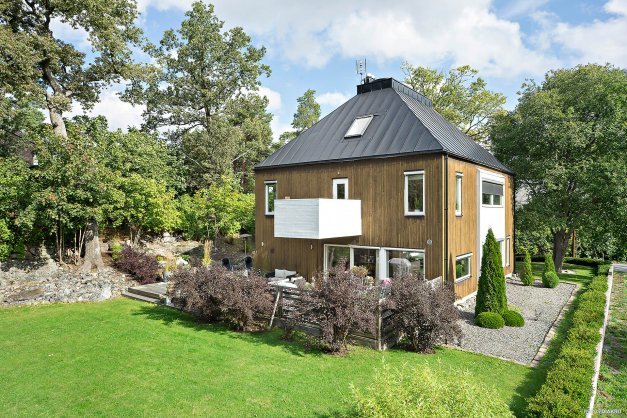 Modern villa designad av Tomas Sandell i Saltsjöbaden med träfasad, stort fönsterparti och lummig trädgård.