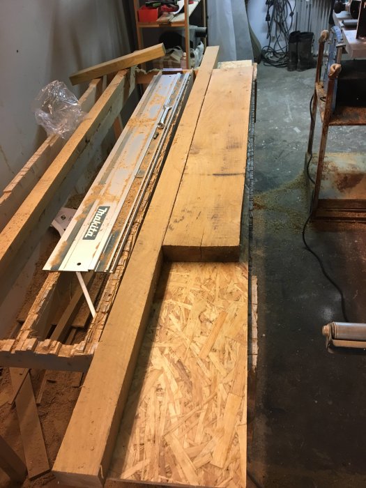 Upphyvlade och frästa ekplank bredvid verktyg på ett städigt arbetsbord, förberedda för att bli ett träräcke.