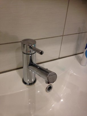 Kromad tvättställblandare Noro i mycket gott skick monterad på vit handfat med kakelvägg bakom.