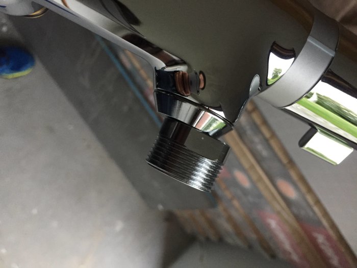 Närbild av en kromad Hansgrohe takduschanslutning med rörtrådar och justerbara delar.