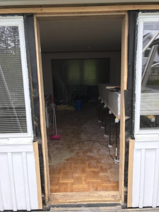 Renoveringsprojekt där en altandörr är borttagen för att skapa en groventré, visar trägolv och verktyg inuti huset.