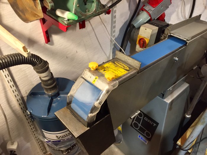 Verkstadsutrustning med svetsat plexiglas stänkskydd, kopplad till utsugsystem med gnistfälla.