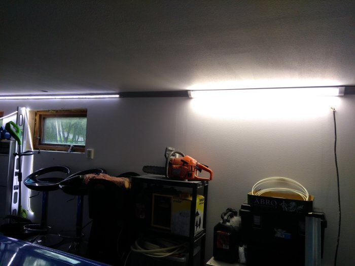 Nyinstallerad LED-armatur på vägg som lyser upp ett garage med synlig tejp på LED-list.