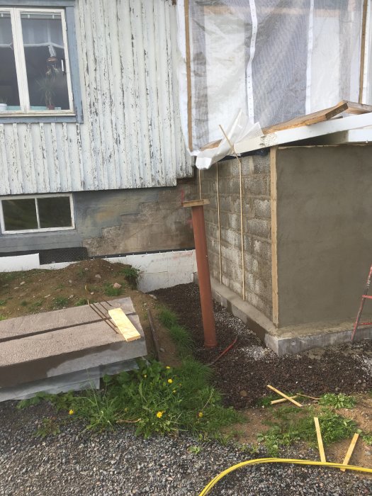 Nyputsad vägg vid husrenovering med rivet tak och förberedelse för nya fönster och stomme.