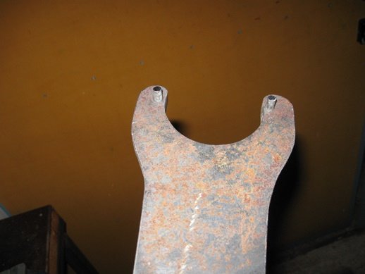 Rostig metallkomponent med två hål, troligen del av en äldre smärgelmaskin.