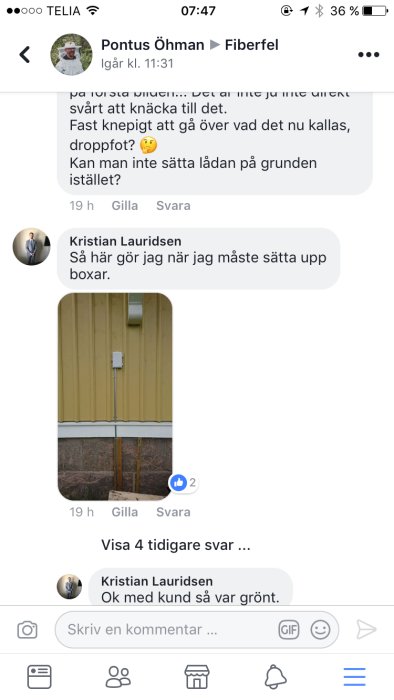 En fasadbox för fiberinstallation monterad på en gul trävägg med kabel som leder neråt.