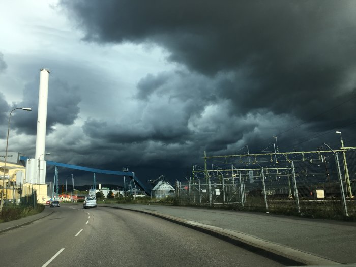 Mörka, hotfulla moln över Göteborgs gator och industriområde under en stormig dag.