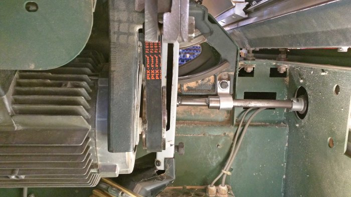 Multi-ribbed belt not aligned properly on the pulleys of a machine, potential misalignment issue visible.