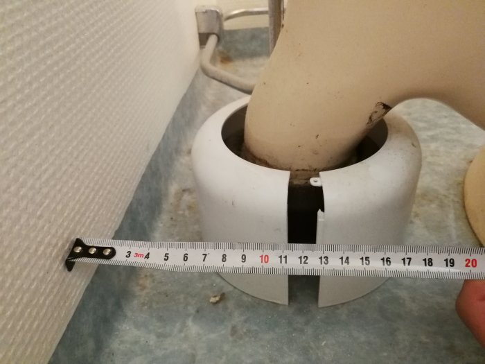 Måttband visar 90mm avloppsrör för toalett, i behov av städning.