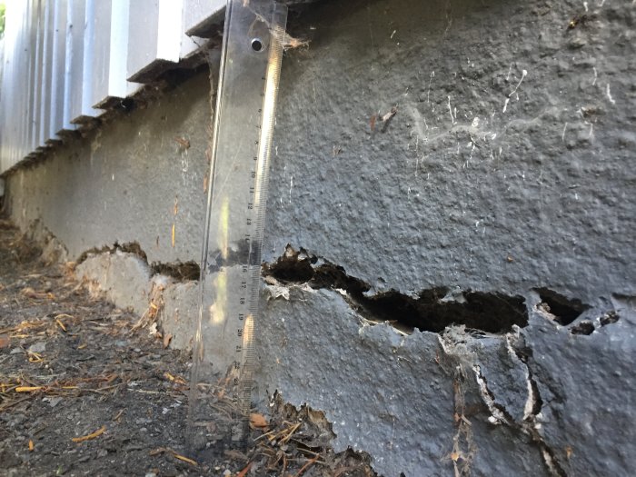 Mätsticka vid en 2 cm bred och 17 cm djup spricka i lecablockens grund på ett hus.