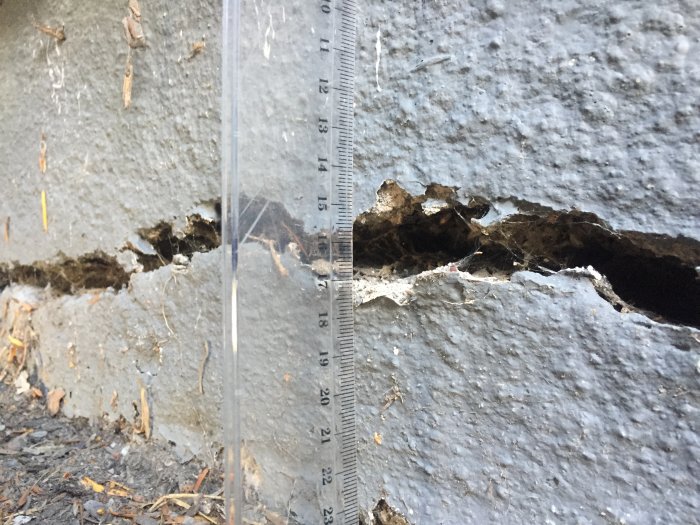 Spricka på cirka 2 cm bredd och 17 cm djup i grått lecablock, uppmätt med linjal.
