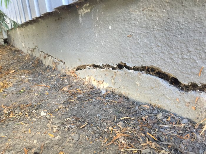 Spricka i grunden av lecablock som är ungefär 2 cm bred och synligt djup, längs husets yttervägg.