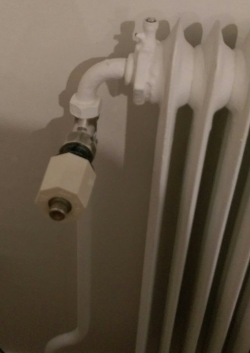 Radiator med termostatventil och synlig upphängning, möjlig källa till knarrande ljud.