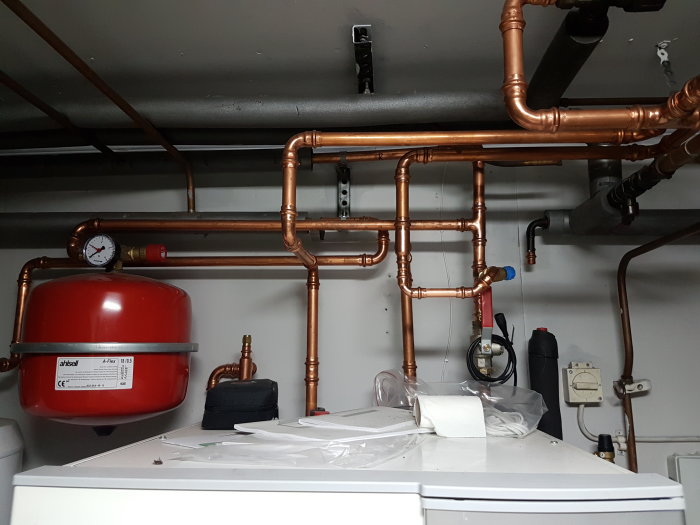 Expansionskärl och kopparledningar i en pannrumsmiljö med manometer som visar lågt tryck.