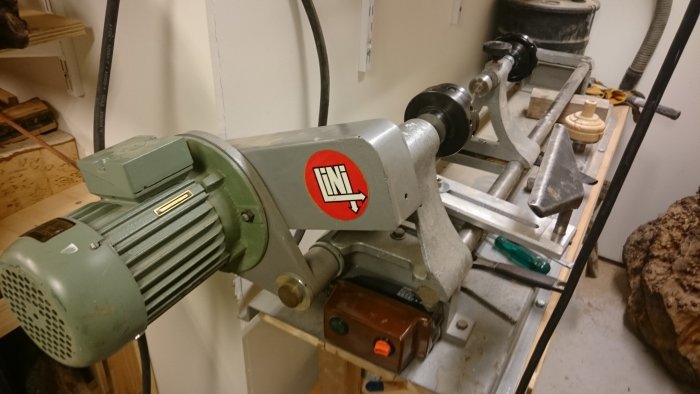 En äldre svarv med en röd och vit LINI-dekal och mekaniska komponenter, inuti ett verkstadsutrymme.