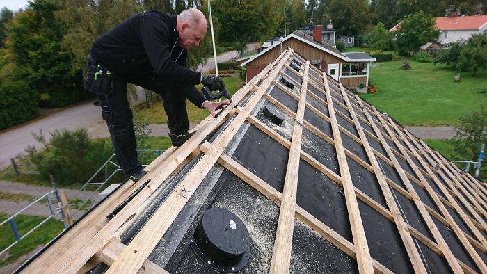 En person monterar läkt på ett tak med underlagspapp, redo för takpannor.