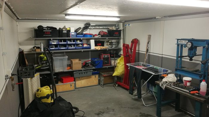 Garage med nybyggda hyllor och verktyg i förberedelse för installation av billyft.