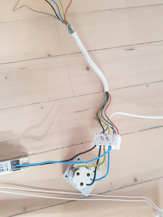 Elinstallation med flera kablar och en LED-transformator på ett trägolv.