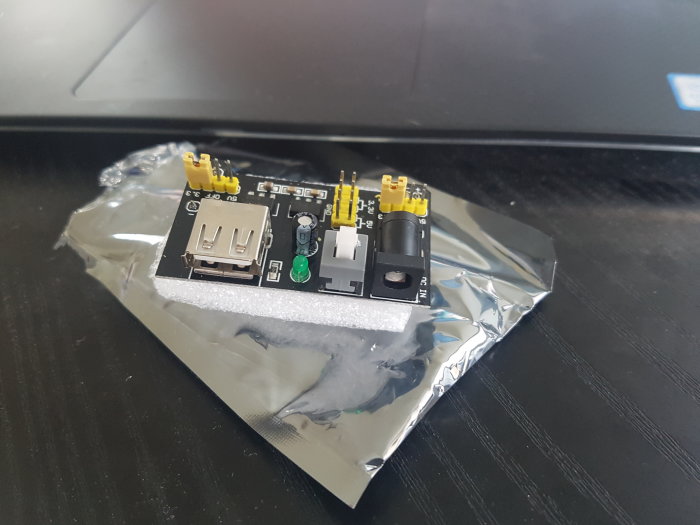 Elektronisk modul med DC-ingång, on/off-knapp, USB-port, och jumper för 3,3/5V, oidentifierad på folie.