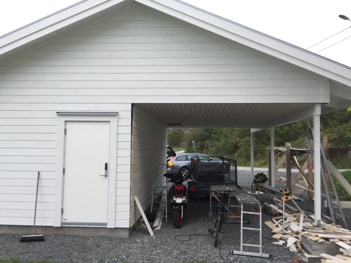 Nybyggd carport med vit panel och innertak, verktyg och byggmaterial synliga.