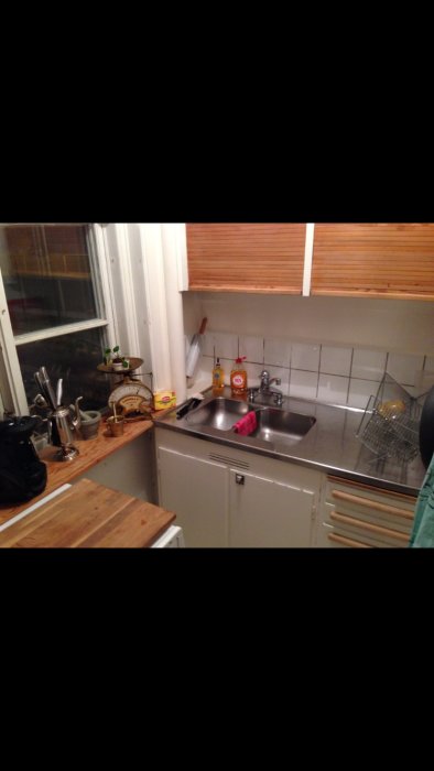 Retrokök med rostfri diskbänk, kakel och träskåp ur bruk, redo för renovering.