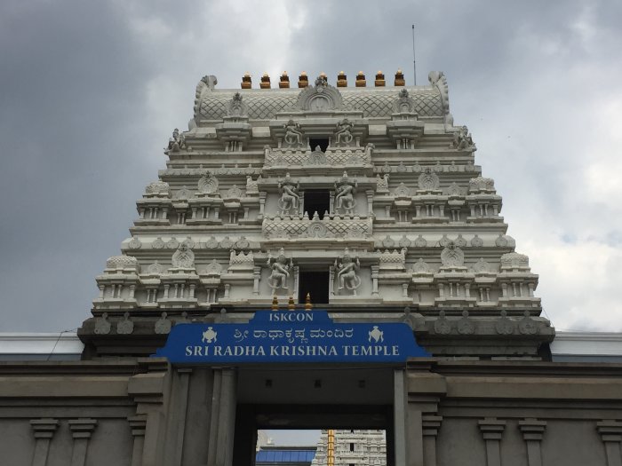 Gopuram av ISKCON Sri Radha Krishna-templet i Bangalore med molnig himmel i bakgrunden.