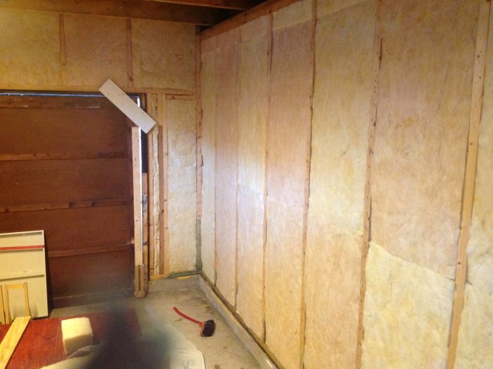 Isoleringsarbete i ett pågående byggprojekt med synliga isoleringsplattor på väggar och hörn.