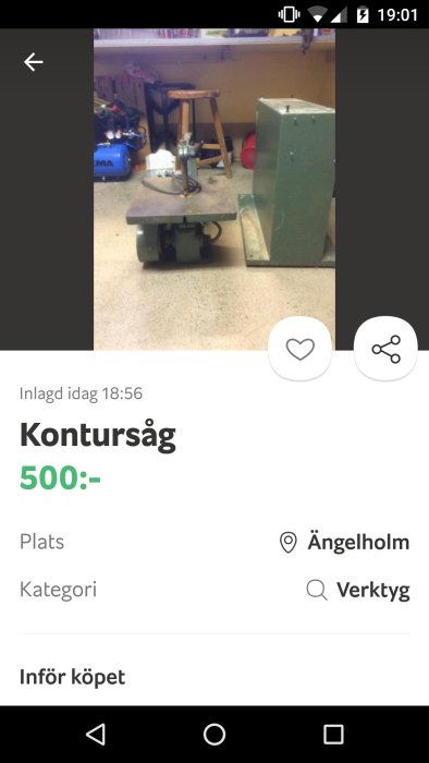 Kontursåg placerad på ett verkstadsbord i en garageverkstad med verktyg och förvaringsskåp i bakgrunden.