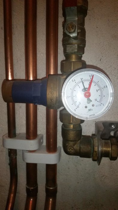 Vattenrör med manometer visar 4,4 bar, omgiven av kopparledningar och ventil.