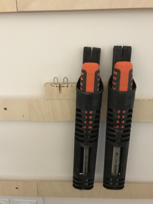 Två styckverktyg på en plywoodvägg med French cleat-system för verktygsförvaring.